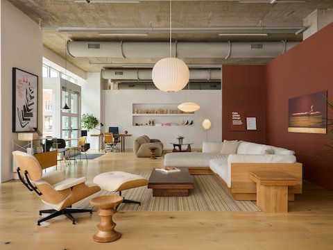 A wood rectangular coffee table in front of a white, L-shaped Pawson Drift sofa across from a white Eames Lounge Chair.
