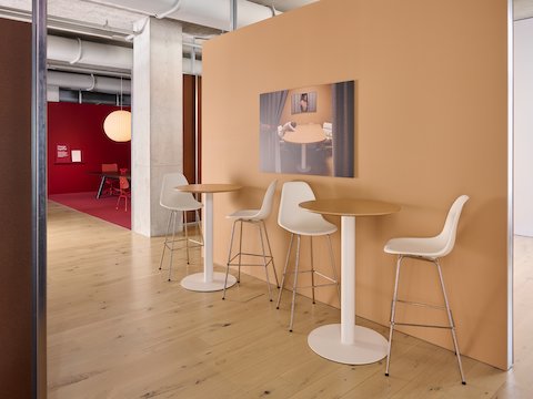 Two white high-top Headway café tables, each flanked by two white bar-height Eames stools.