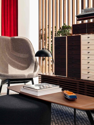 A side chair with tan upholstery in the corner of a private office with a low wooden table and storage drawers on the side.