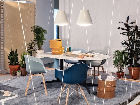 An office space with About A Chairs and Eames Molded Plastic Chairs in shades of blue pulled up to a white oval Nelson Pedestal Table with a white marble top. Two white Sinker Pendants hang above the table.