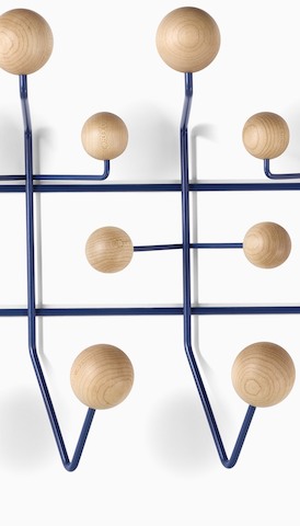 Close-up of an Eames Hang-It-All with wood knobs for hanging storage. Select to go to the Accessories product page.