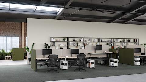 Un espace bureau avec le système de bureaux Ratio avec les écrans de séparation Bound en vert et gris, et des sièges Aeron noir. 