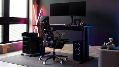 Uma cadeira de jogos Embody configurada com um teclado de jogos, mouse e monitores duplos.