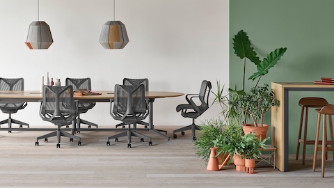 A Y base Headway conference table surrounded by seven Cosm chairs in an open conference space with a Headway communal table with stools nearby.