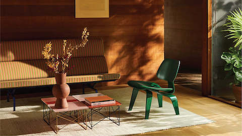 Herman Miller x HAY, cenário externo de cadeiras Wire verde, preta azul e amarela e mesa Eames vermelha de ferro