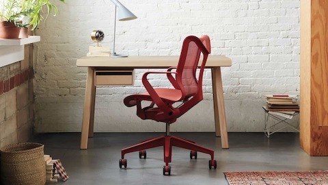 A red Cosm chair at a desk in a home office setting.