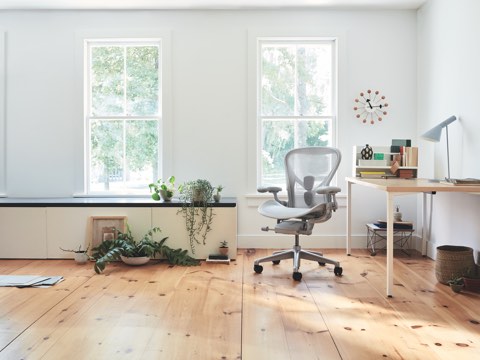 Um ambiente de home office, com a mesa Everywhere, uma cadeira Aeron Mineral e o acessório Ubi