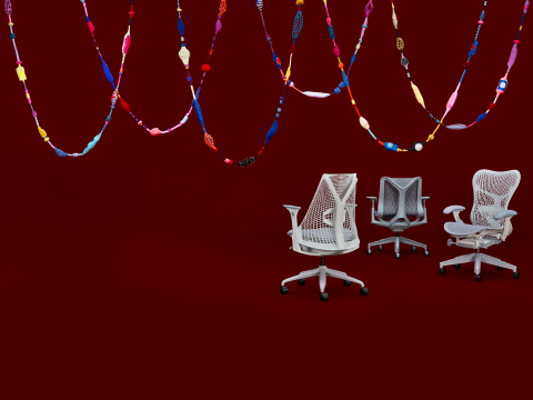 Line up of white Herman Miller office chairs on a red background.