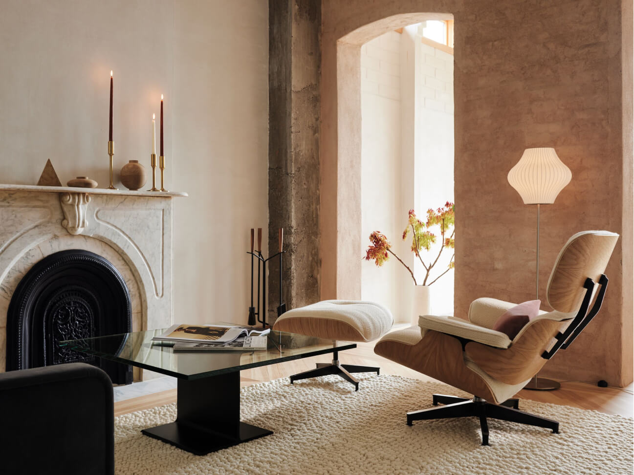 A cozy living room of creamy and natural wood hues featuring sparse modern furnishing and warm lighting