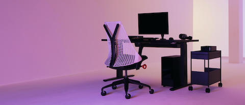 白色靠背的Sayl电竞椅和全黑的电竞设备位于房间中央，渐变的粉紫色灯光照耀其上。  