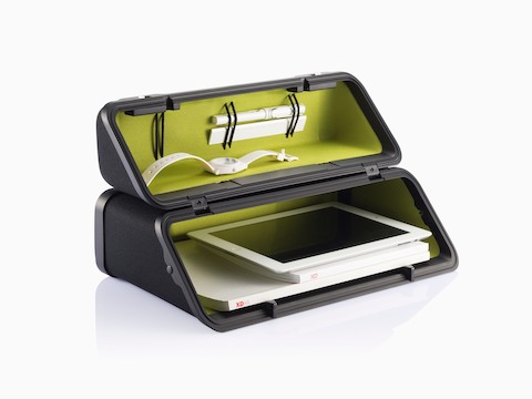 An Anywhere Case with a green lining, positioned horizontally and containing a watch, booklets, and tablet computer.