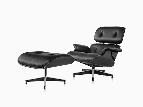 Angled view of an Eames Lounge Chair and Ottoman with black leather upholstery and a black shell.