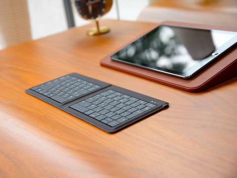A keypad and tablet computer on a wood desk.