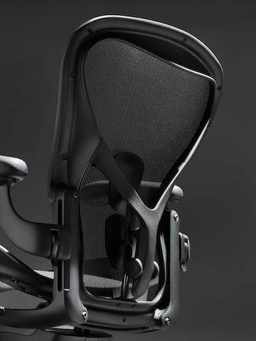 Silla Aeron en ónix ultra mate sobre fondo negro con apoyo de respaldar ergonómico, con vista en ángulo del respaldo de la silla.