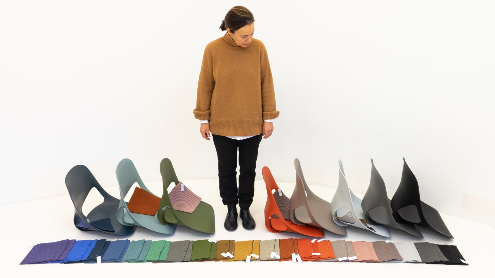 Carola Zwick from Studio 7.5 standing and looking at the shell and material colors available for the Zeph chair.