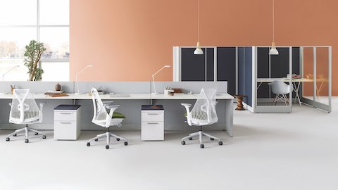 White Sayl ergonomic office chairs at Action Office workstations with storage pedestals near a pair of Action Office private offices.