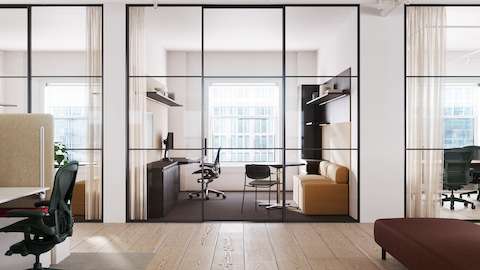 A black Aeron Chair with a polished base and frame in a private office with a desk and sofa.