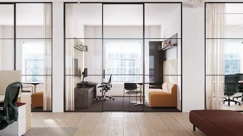 Una Silla Aeron negra con base y estructura pulidas en una oficina privada con escritorio y sofá.