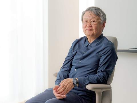设计师 Naoto Fukasawa 坐在浅棕色的高靠背 Asari 椅子上。