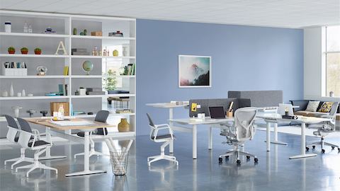Eine Collaboration-Umgebung mit einer Reihe von Sitz-Stehtischen und einem rechteckigen Tisch von Atlas Office Landscape.