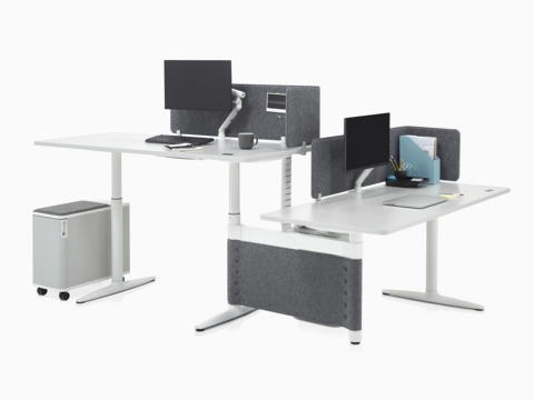 两张高度可调式Atlas Office Landscape办公桌呈90度夹角摆放在一起，一张调整为站姿高度，另一张调整为坐姿高度。