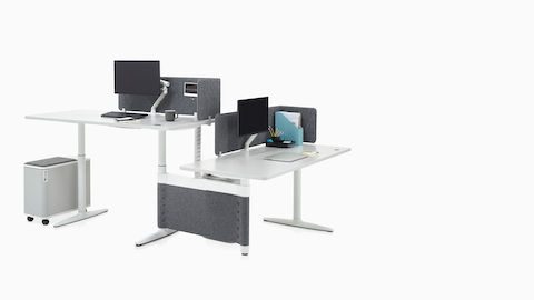 Height-adjustable Atlas Office Landscape desks in a 90-degree configuration, one at standing height and one at seated height.