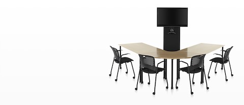 Chaises de bureau noires Caper autour d'une table en bois en forme de U face à un chariot noir AV / VC One avec grand écran numérique et webcam.