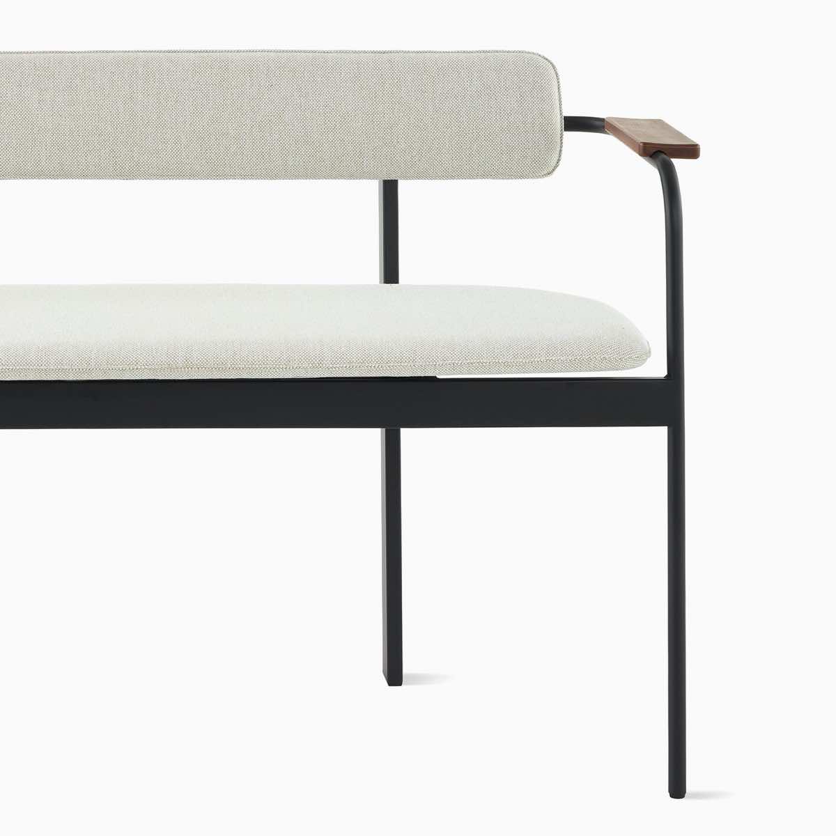 A Betwixt Bench with grey fabric seat and backrest, with walnut arms and a black frame.
