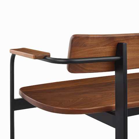 A close up of a Betwixt Bench with walnut seat, backrest, and arms, with a black frame.