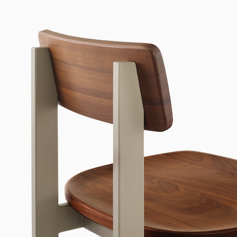 A close up of a Betwixt Chair with walnut seat and backrest with a grey frame. 