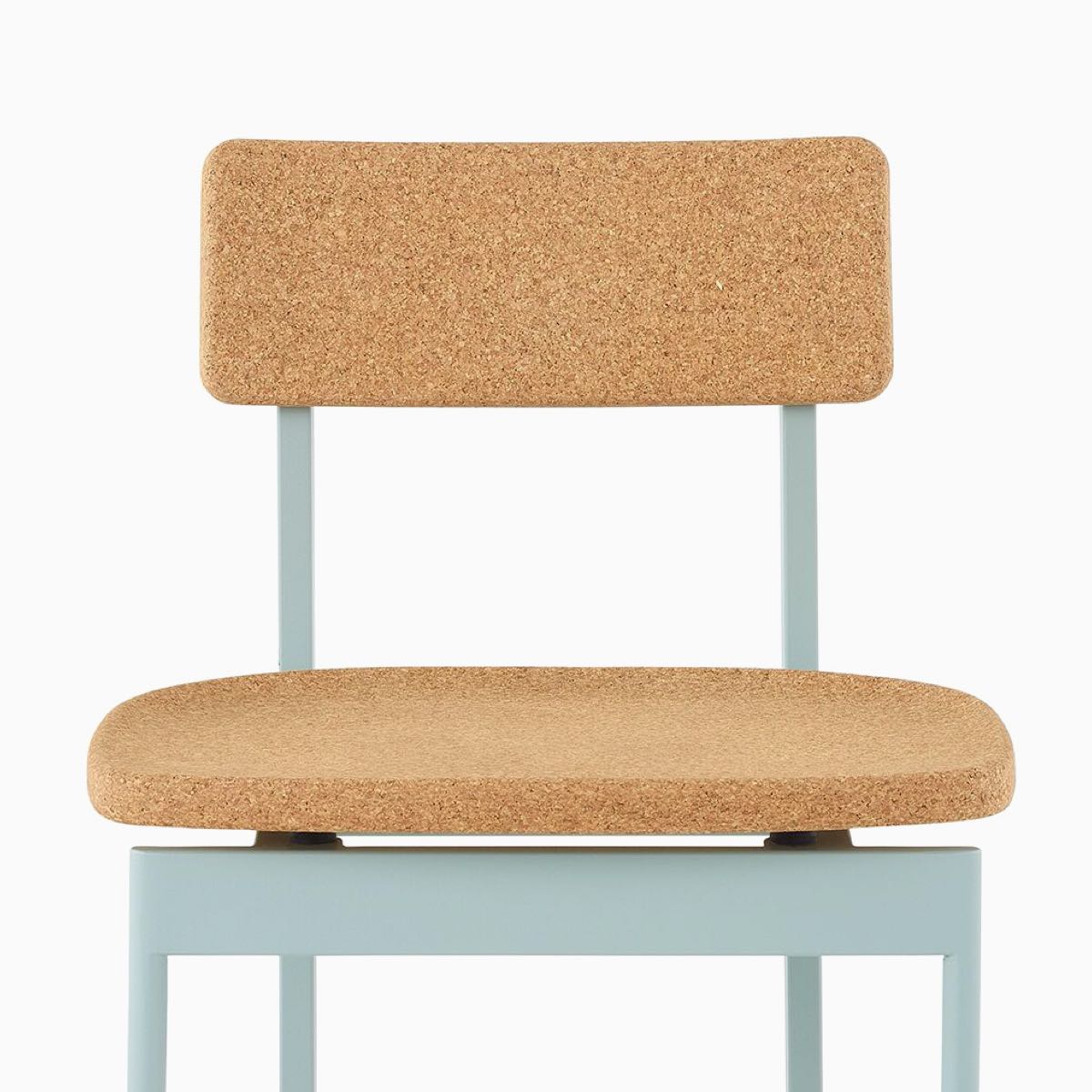 A Betwixt Chair with a cork seat and backrest with a glacier frame.