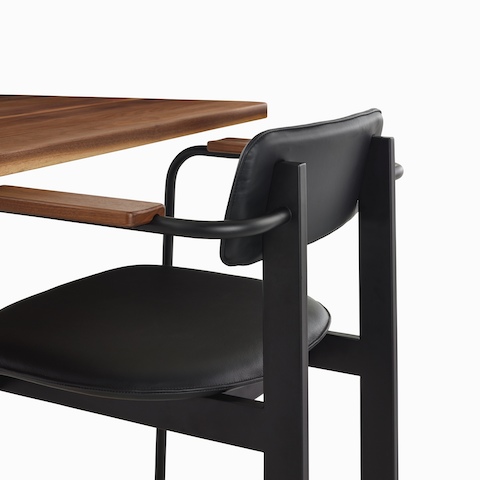 Ein schwarzer Betwixt Stuhl an einem Holztisch.