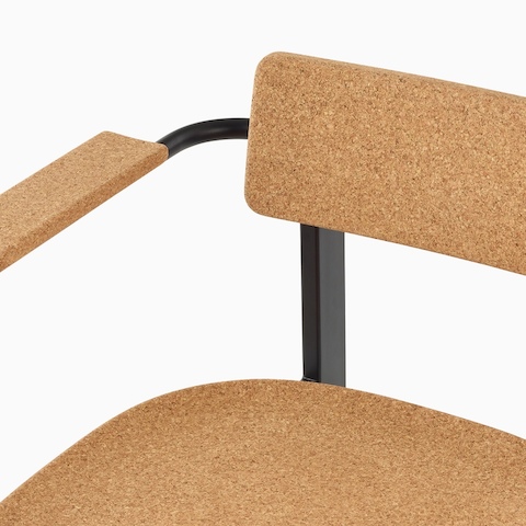 A close up of a Betwixt Chair with cork backrest, seat, and arms. 