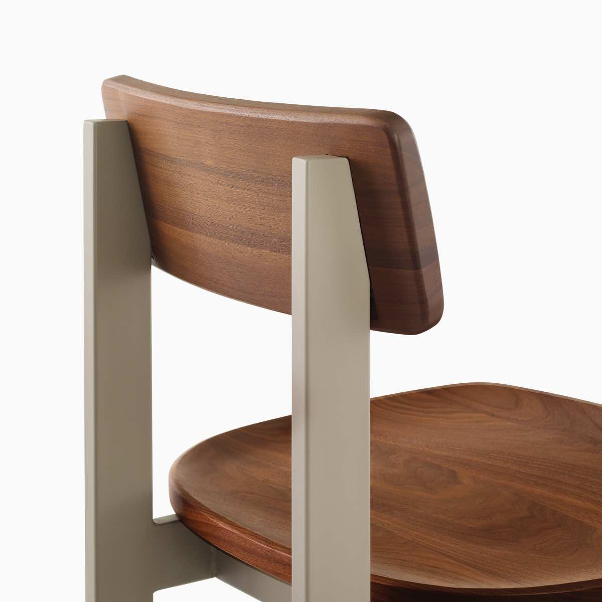 Een close-up van een Betwixt-stoel met walnoot zitting en rugleuning met een grijs frame.