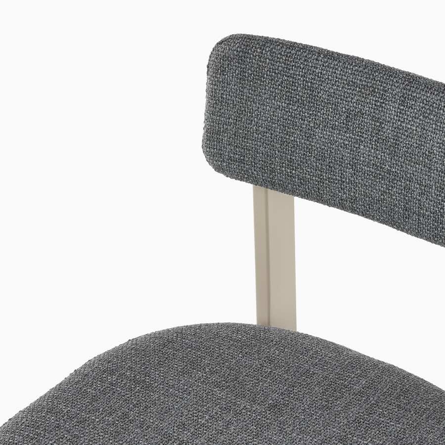 A close up of a Betwixt Stool with fabric backrest and seat, with a grey frame.