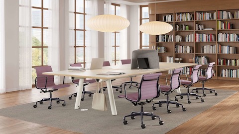 Rectangular Boa Table, seated height, oak top, white base, in a library setting with Eames Aluminum Group chairs.