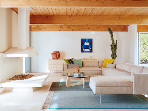 休闲风格环境中的奶油色Bolster沙发系列沙发（带转角和休闲躺椅单元）和Noguchi桌子。