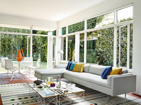 休闲风格环境中的灰色Bolster沙发系列沙发（带休闲躺椅单元）和Eames钢丝底座矮桌。