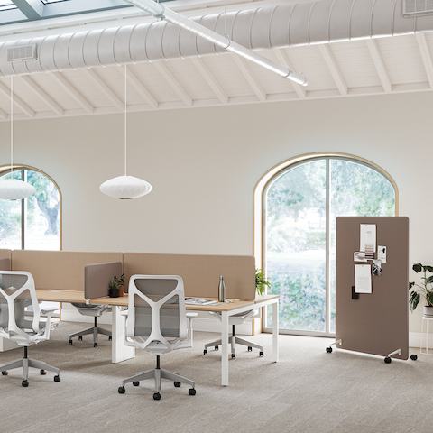 A bright office space with Layout Studio workstations with brown Bound Screens, Cosm Chairs and a brown Bound Mobile Screen in the background.