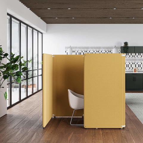Een kantooropstelling met een geel vrijstaand Bound-scherm in een hokje-toepassing en groene Bound-schermen op Nevi Link-werkstations met grijze Lino-stoelen op de achtergrond.