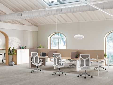 Eine helle Büroumgebung aus Layout Studio Arbeitsplätzen mit braunen Trennwänden, Cosm Stühlen sowie einer braunen mobilen Trennwand im Hintergrund.