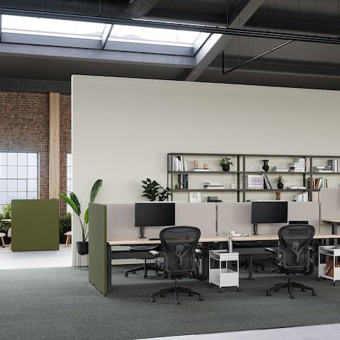 Agencement de bureau avec des postes de travail Ratio, des écrans de séparation verts et gris et des sièges Aeron noirs. Agencement de bureau avec des postes de travail Ratio, des écrans de séparation verts et gris et des sièges Aeron noirs.