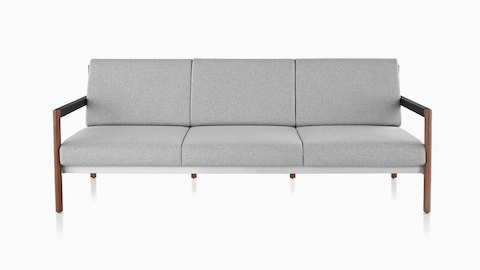 Ein Brabo Sofa mit hellgrauem Textilbezug, Leder- und Metalldetails und sichtbarem Holzrahmen. Von vorne betrachtet.