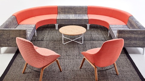 A lounge setting with naughtone seating, including Symbol modular seating in gray and red and Always lounge chairs in red tones.