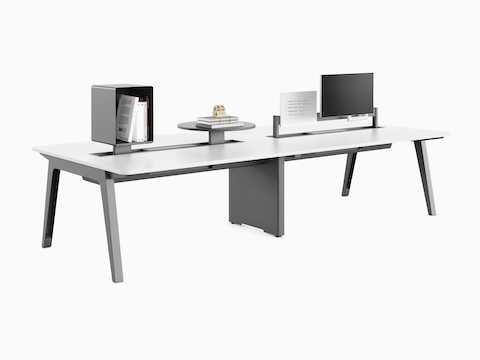 Byne System desks with Optimis legs and a universal middle leg in a 4-seat setting, with toolbars mounted with different accessories.
