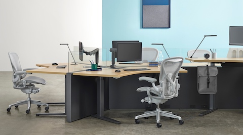 Una estación de trabajo Canvas Channel con mesas Renew de altura ajustable y sillas para oficinas Aeron gris claro.