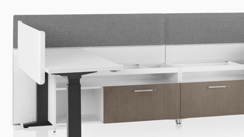 A close-up image of a Canvas Channel workstation with lower storage, grey fabric screens, and Motia height-adjustable tables.