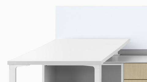 A close-up image of a Canvas Dock workstation in light wood with white surfaces and lower storage.