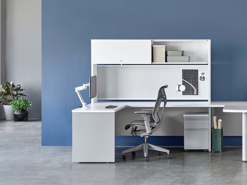 White and gray Canvas Metal Desk with overhead storage, peninsula surface, and gray Cosm Chair.