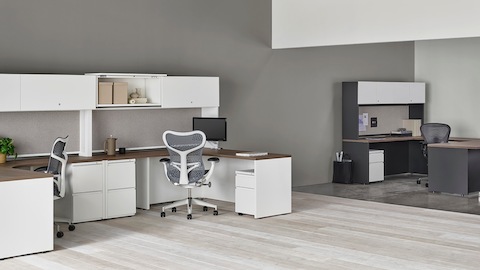 A pair of white Canvas Metal Desks with storage hutches, gray Mirra 2 Chairs, and a dark grey private office in the background.